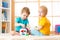 Kids playing with logical toy on soft carpet in nursery roomor kindergarten. Children arranging and sorting shapes or sizes.