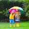 Kids playing in the rain under colorful umbrella