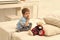 Kids playing with toys. Child in bedroom with silence gesture. Kid put plush bear near pillows and alarm clock, luxury