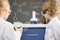 Kids in protective glasses and lab coats making experiment in chemical laboratory