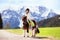 Kids riding pony. Child on horse in Alps mountains