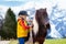 Kids riding pony. Child on horse in Alps mountains