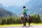 Kids riding pony. Child on horse in Alps mountains