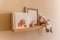 Kids room decor, wooden floating shelf interior child bedroom, empty wooden picture frame, books, poster blank canvas
