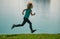 Kids running or jogging near lake on grass in park. Sporty child boy runner running in summer park. Active kids, sport