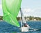 Kids sailing small sailboat head-on closeup with a fouled green spinnaker