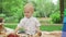 Kids sitting on blanket together in park. Toddler taking strawberry from bowl