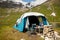 Kids, sitting in front of a piched tent in nature, enjoying wild camping. Family vacation