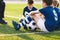 Kids Sitting on Grass Soccer Pitch. Boys in Blue Football Jersey Shirts. Happy Kids on Football Training Camp