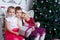 Kids sitting under Christmas magenta tree with gift-box