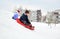 Kids sliding on sleds down snow hill in winter