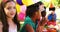 Kids standing near table laid with food and celebrating a birthday