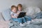 Kids with tablet. Two boys twins toddlers looking cartoon at tablet lying on the bed.