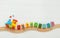 Kids toy train with numbers on railway on white wooden background with copy space