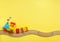 Kids toy train with numbers on toy wooden railway on yellow background with copy space