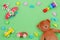 Kids toys background frame with teddy bear, wooden plane, cars and blocks on green background