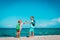 Kids travel on beach, boy and girls with backpack high five at sea