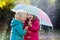 Kids with umbrella playing in autumn shower rain