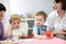 Kids view images in book at table in nursery