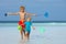 Kids walk on a beach hold buckets and hoop-net catching crabs