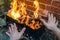 Kids warming their arms over fire and grill on red brick wall background in backyard