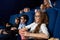 Kids watching movie in cinema, holding popcorn buckets.