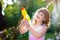 Kids with water gun toy in garden. Outdoor fun