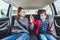 Kids wearing anti virus masks and using digital tablets in the car.