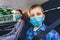 Kids wearing anti virus masks and using digital tablets in the car. Kids are travelling in car during coronavirus