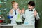 Kids in white coats with chalkboard behind in laboratory, scientists kids team concept