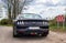 Kiel, Germany - 30.April 2022: Rear view on a black Ford Mustang model 2018 sports car parked on a sandy road