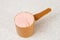 Kiev, Ukraine - May 31, 2020: A full measuring cup of pink protein powder from optimum nutrition with strawberry flavor