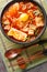 Kimchi Soondubu Jjigae  classic Korean stew features silken tofu in a fiery kimchi broth closeup on the bowl. Vertical top view