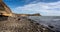 Kimmeridge Bay with rocky shore line and fossil hunters, with The Clavell Tower in the background in Kimmeridge, Isle of Purbeck,