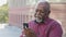 Kind calm senior black grandfather makes video call, looks at smartphone camera, african american mature man elderly