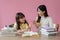 A kind and caring Asian female teacher or sister helps a young, adorable girl do homework