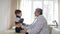 A kind caring experienced elderly person, a professional pediatrician, conducts a medical examination of a small boy