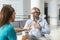 Kind female doctor embracing encouraging happy senior male patient in hospital. Happy healthy older man and his physician enjoying