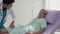 A kind male nurse converses with an elderly patient who is resting in bed. After a successful surgery, an elderly man is fully
