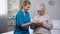 Kind nurse giving birthday cake to aged lonely woman, taking care in old age