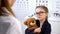 Kind optician giving teddy bear to upset child patient, psychological help