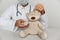 Kind pediatrician in mask treats sick teddy bear. Child healtcare and treatment concept