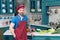 Kind tattooed chef in red apron and red cap standing on kitchen