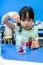 Kindergarten girl using droplet to add red color into a cup on b