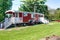 Kindergarten in a red, wooden construction trailer with a white veranda and playing children. Countrylife at it`s best!