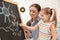 Kindergarten teacher and little child drawing on chalkboard. Learning and playing