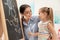 Kindergarten teacher and little child near chalkboard. Learning and playing