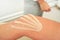 Kinesiology tape in body color cut to thin stripes applied to knee of female patient, closeup detail