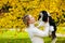 The King Charles Spaniel dog and the owner walk in the warm autumn against the background of yellow leaves. A pet in the arms of a