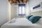 King size bed with white wooden headboard, blue curtain, wooden ceiling